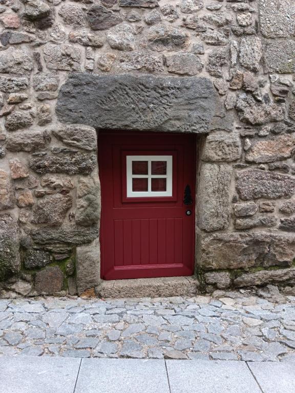 a red door in the side of a stone building at Recanto da Pedra in Linhares