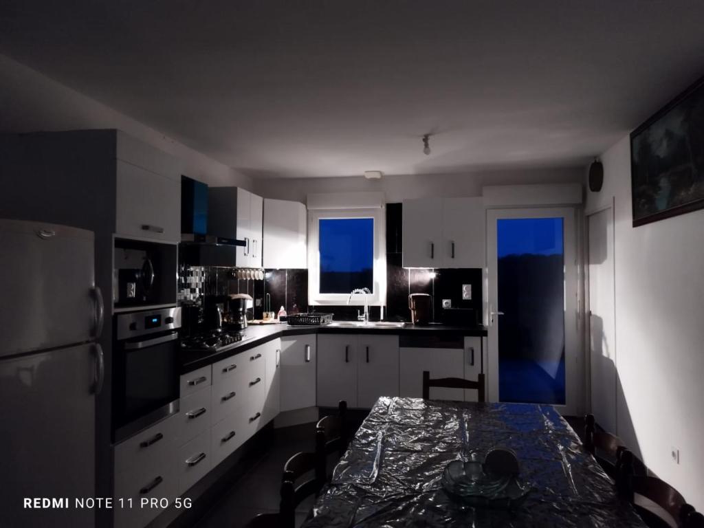 a kitchen with white cabinets and a table in it at La casa en el campo A 20 minutes de Zoo Beauval &amp; 8 minutes de la flamme olympique à Valençay in Vicq-sur-Nahon