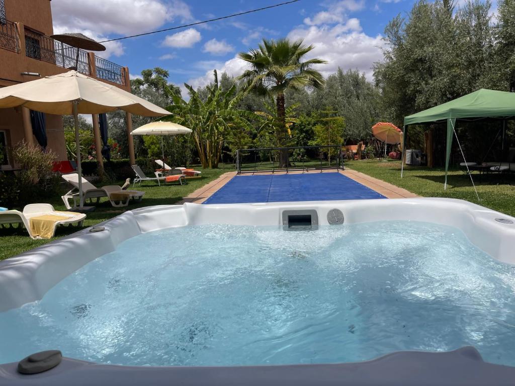 a large hot tub in a backyard with a pool at Ilafe Farmhouse, Villa avec piscine chauffée privée et Jacuzzi pour familles in Marrakesh