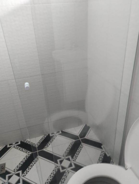 a bathroom with a toilet and a black and white floor at Residência Itaúna in Saquarema