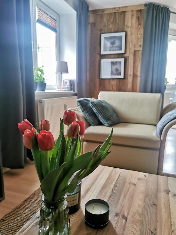 a living room with a vase of flowers on a table at Mozaika Art Apartment PL LT EN in Suwałki