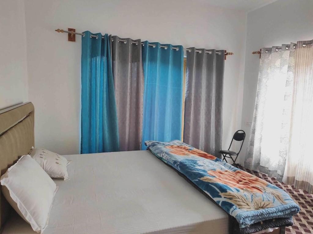 a bedroom with a bed with blue curtains at POP HOME 81129A Skayil Guest House in Nubra