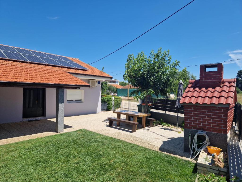 a backyard with a picnic table and a house with solar panels at Holiday Home Gabriela in Sukošan