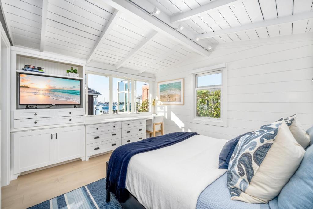 a white bedroom with a bed and a television at Balboa Island Luxury Penthouse Suite With Bay Views in Newport Beach