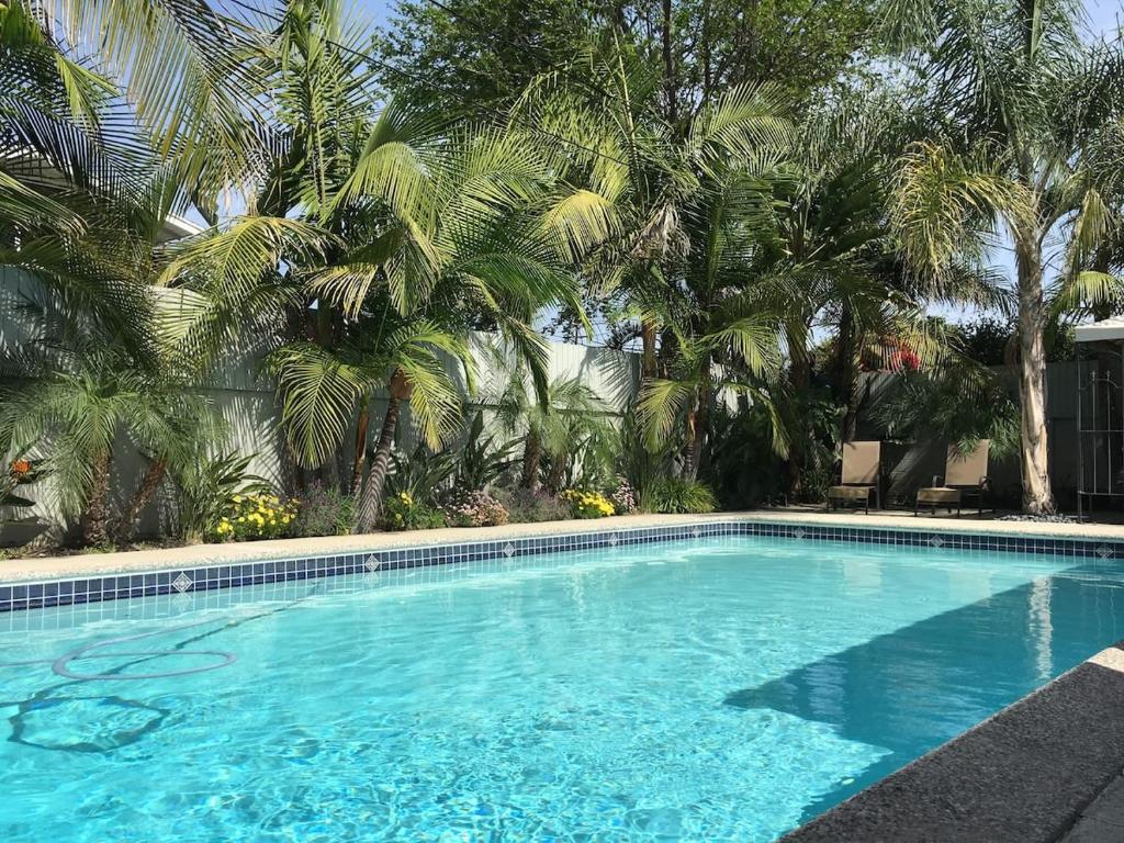 una piscina blu con palme sullo sfondo di Palm Villa Disneyland Pool 4 Bedroom 3 Bath HotTub ad Anaheim