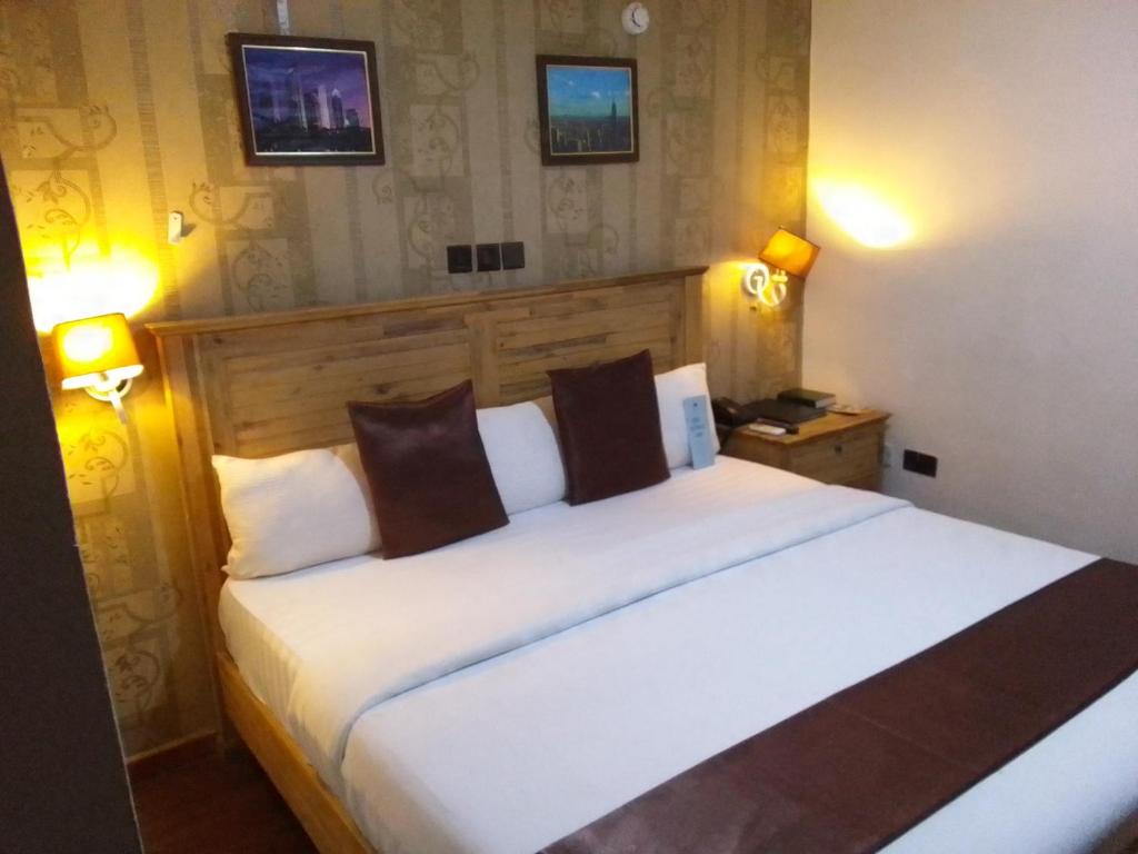 1 dormitorio con 1 cama blanca grande y 2 lámparas en St Theresers apartments lodge4 en Lagos