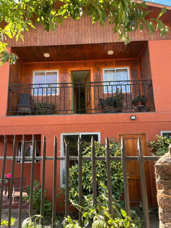 ein orangefarbenes Haus mit einem Balkon und einem Zaun in der Unterkunft Hostal Renacer in Santa Cruz