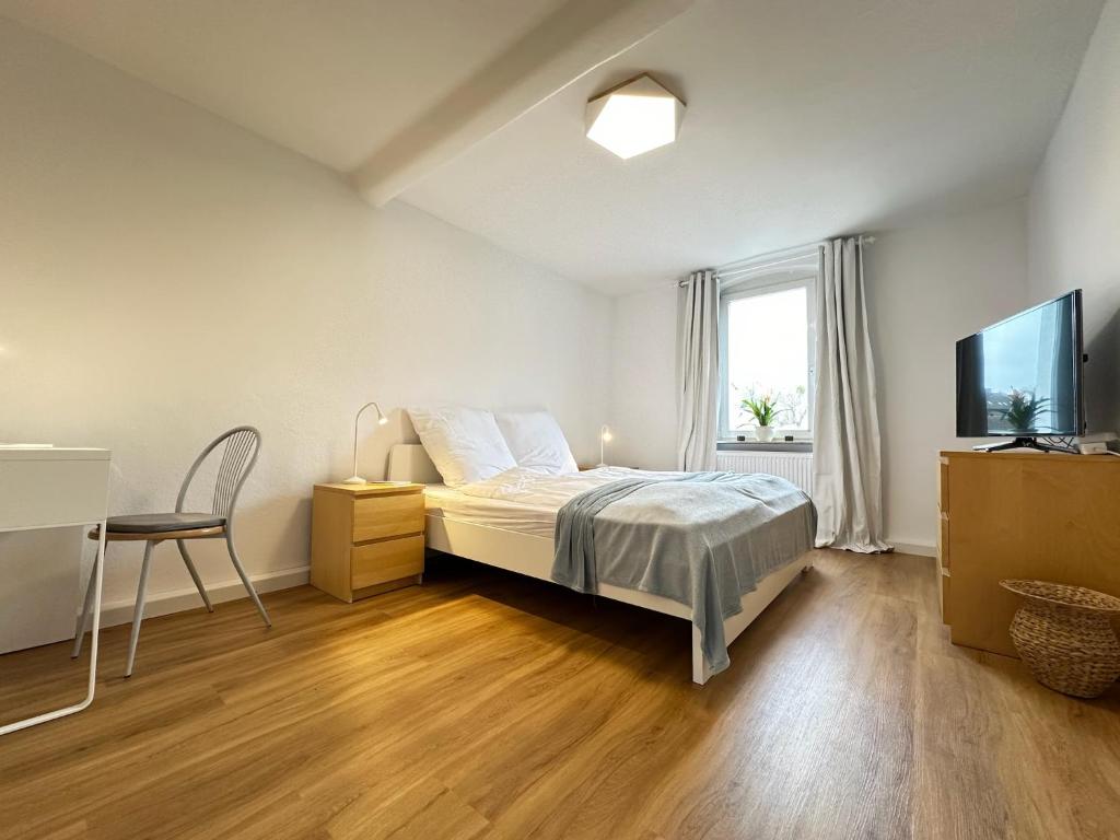Dormitorio con cama, escritorio y TV en Cleo Apartments en Kassel