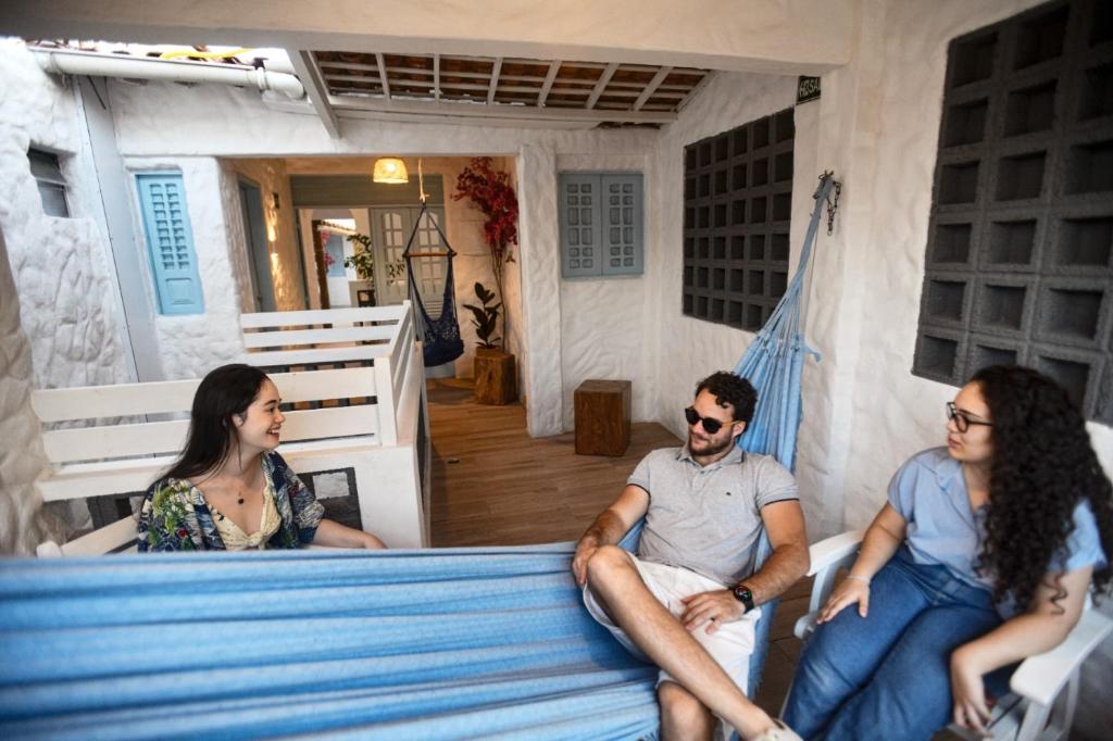 un groupe de trois personnes assises sur un lit dans l'établissement Vila DuJu, à Porto de Galinhas