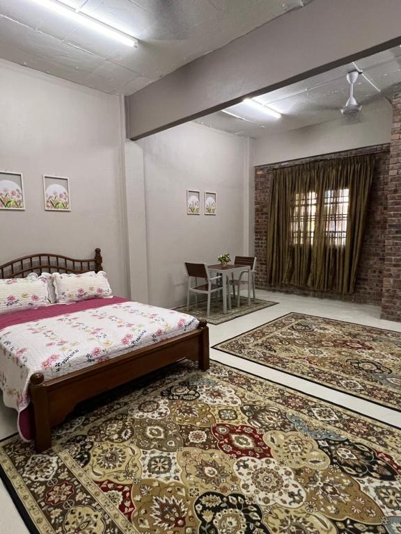 een slaapkamer met een bed, een tafel en een tapijt bij RUMAH CHANGGONG Studio in Kota Bharu