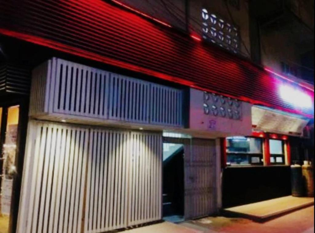 uma fachada de um edifício à noite com luzes vermelhas em Four Season 1 Airport Guest House em Carachi
