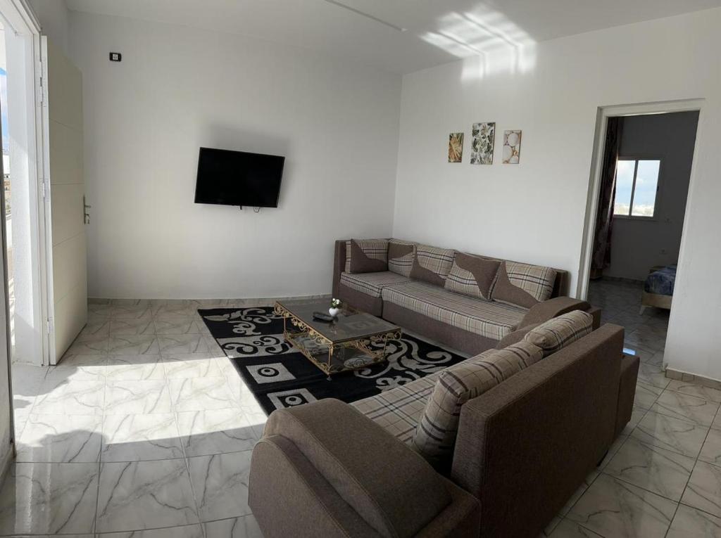 uma sala de estar com um sofá e uma televisão em Dyar Amina em Midoun