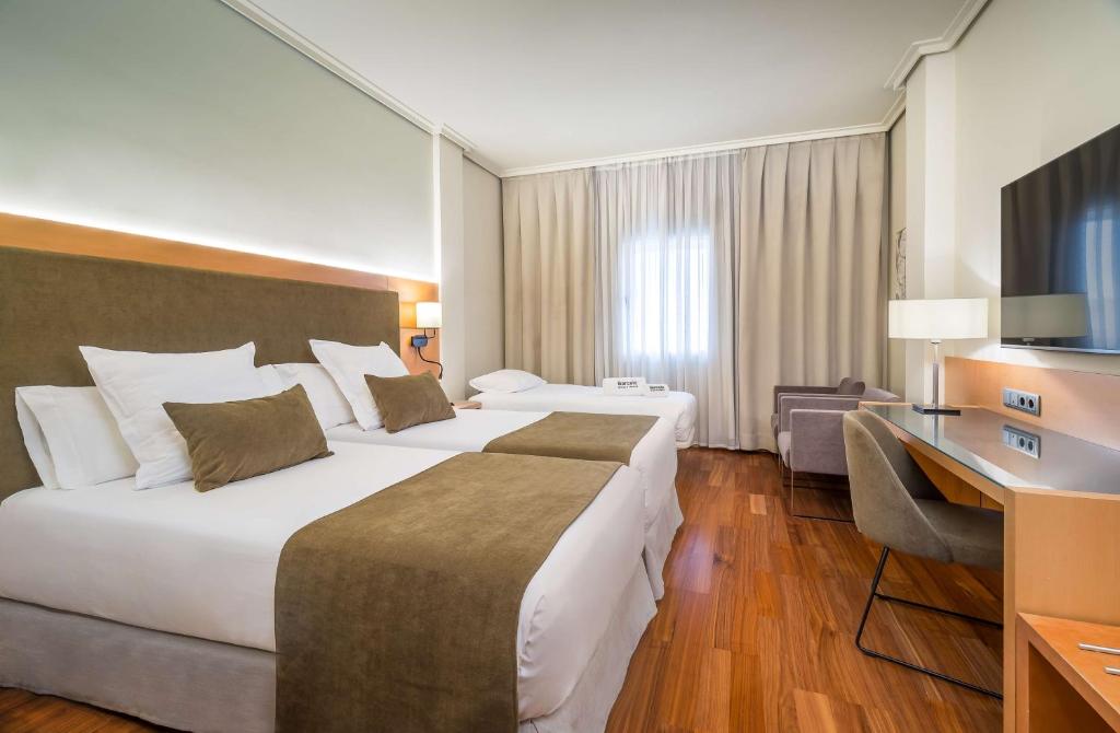 a hotel room with two beds and a desk at Barceló Murcia Siete Coronas in Murcia