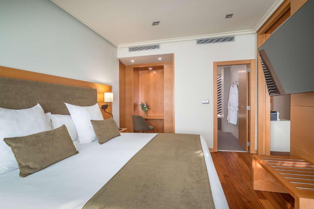 a bedroom with a large white bed and a television at Barceló Murcia Siete Coronas in Murcia