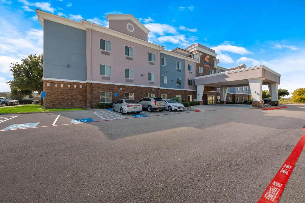 un gran edificio con coches estacionados en un estacionamiento en Comfort Suites, en Bastrop