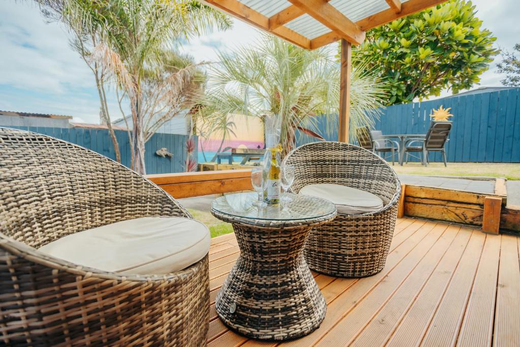 three wicker chairs and a table on a deck at Sunrise Accommodation in Whakatane