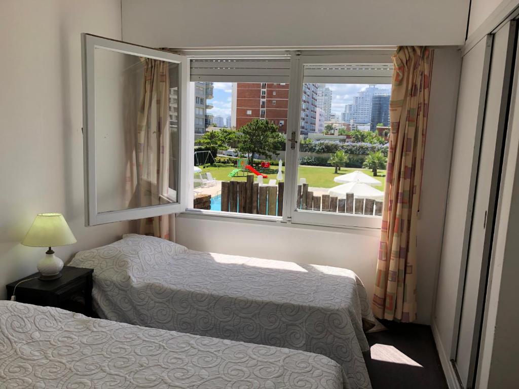 een slaapkamer met 2 bedden en een groot raam bij Hotel Gaudí in Punta del Este