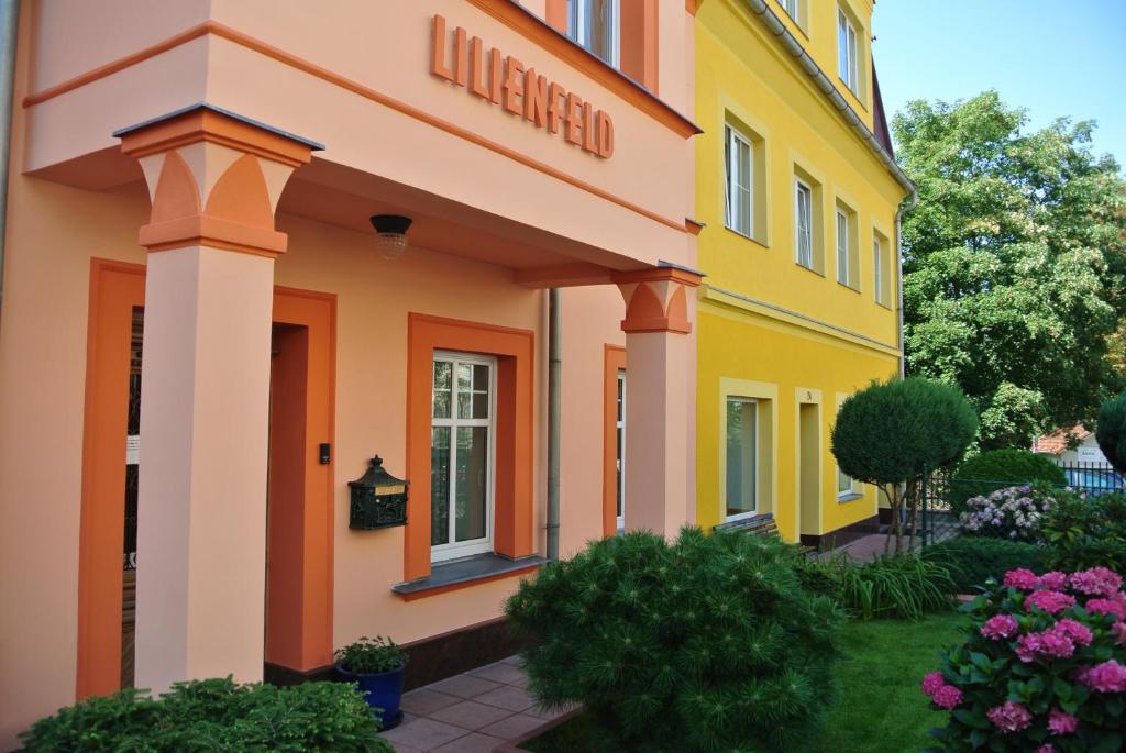 un edificio amarillo y naranja con flores en un patio en Penzion Valkoun-Lilienfeld en Karlovy Vary