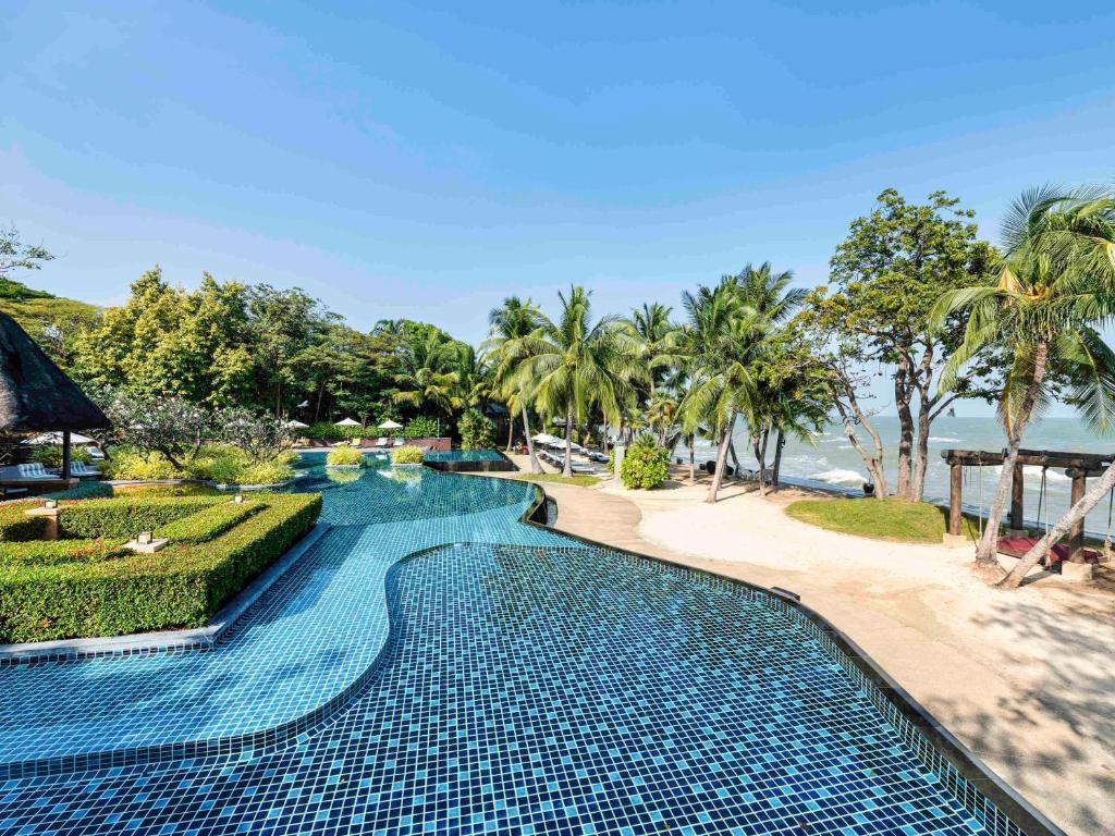 a swimming pool next to the beach at a resort at Mövenpick Asara Resort & Spa Hua Hin in Hua Hin