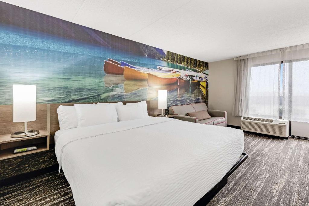 エリーにあるClarion Pointe by Choice Hotelのベッド付きの客室で、壁には絵画が飾られています。