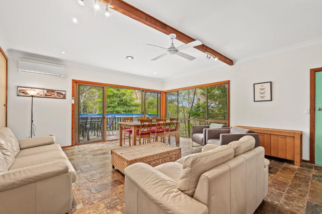 a living room with couches and a table at Leafy Family House, Close to Beach and Surf Club in Macmasters Beach
