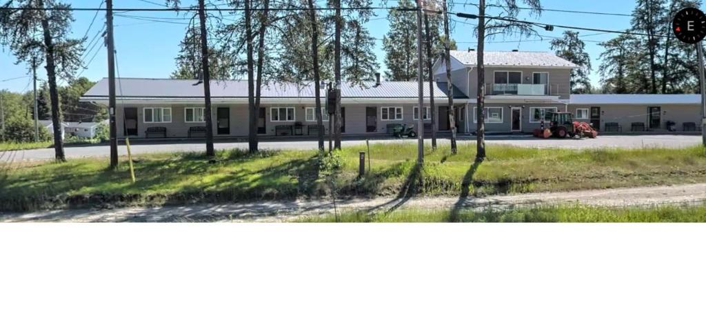 蒂明斯的住宿－Pine Ridge Motel，前面有树木的白色大建筑
