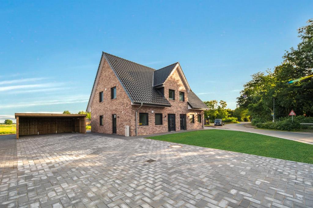 a brick house with a garage on a driveway at Luv in Osterhever