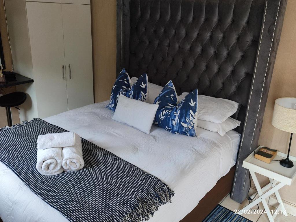 1 cama con almohadas y toallas azules y blancas en Onyx Luxury cottage, en Randburg