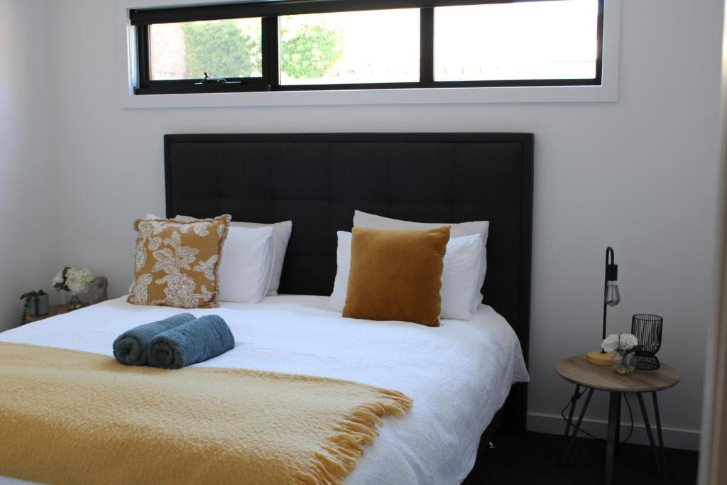 Schlafzimmer mit einem Bett mit einem schwarzen Kopfteil und Kissen in der Unterkunft CBD Elizabeth St Modern Townhouse - Secure Parking in Launceston