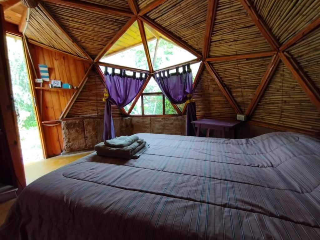 Cama grande en habitación con ventana grande en Casa Arbol Domos en Cafayate