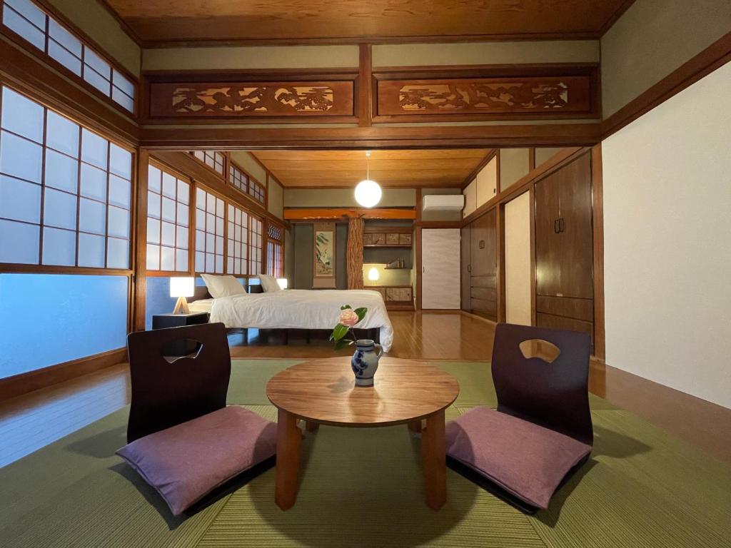 a room with a table and chairs and a bed at 貸切宿KUMANO in Miyazaki