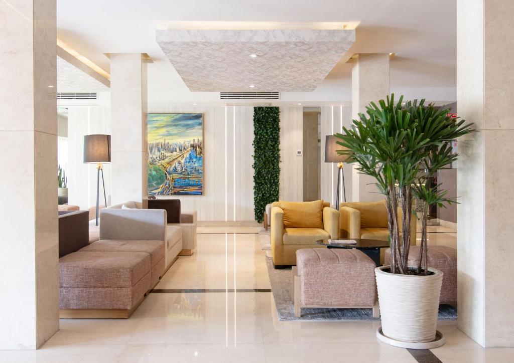 a lobby with couches and chairs and plants at Hotel Plaza Diana in Guadalajara