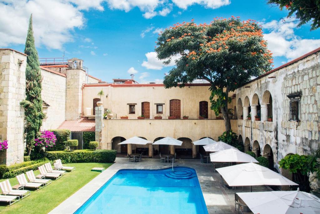 a pool in front of a building with chairs and umbrellas at Quinta Real Oaxaca in Oaxaca City