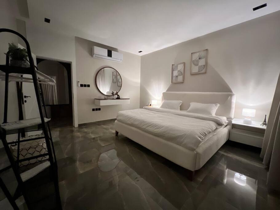 a white bedroom with a bed and a staircase at شقة جديدة بتصميم فاخر نظام مودرن in Riyadh