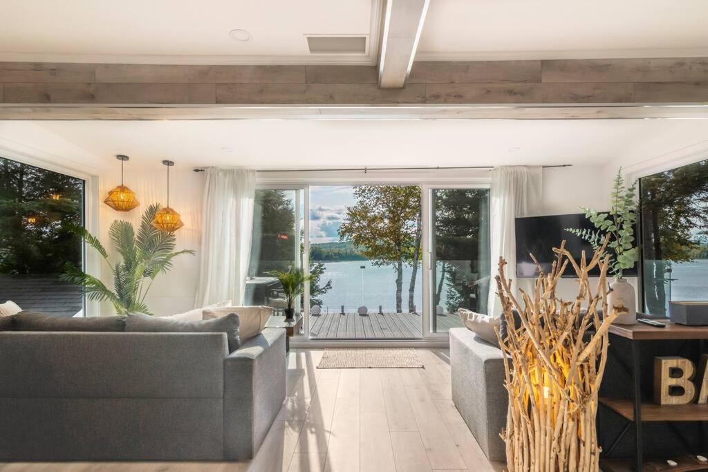 a living room with two couches and a large window at Chalet L’Oasis Zen in Nominingue