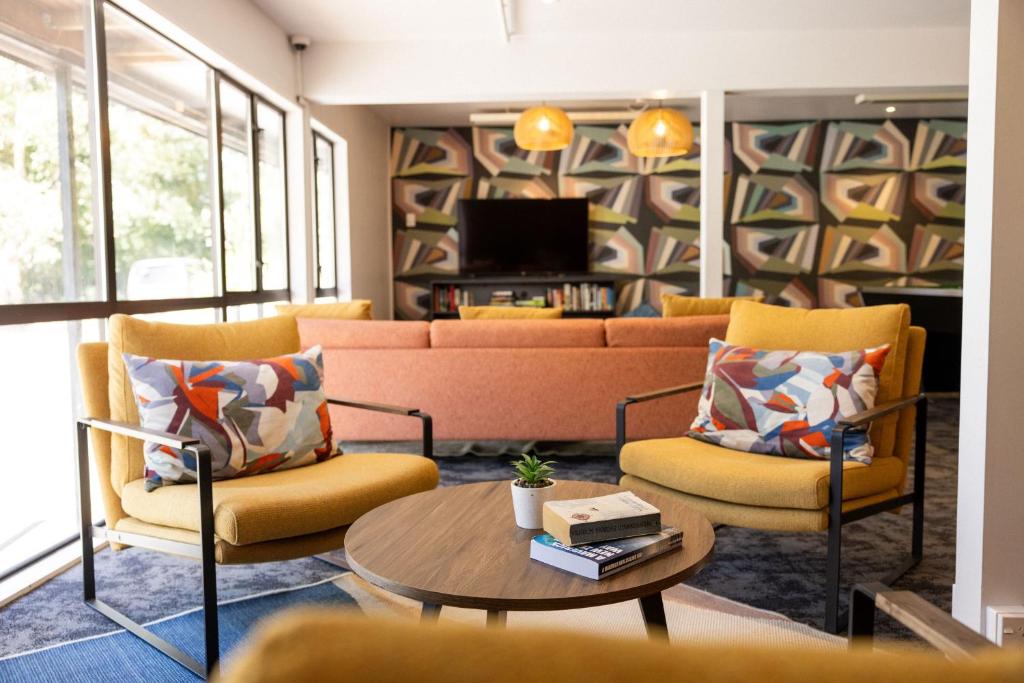Haka House Queenstown Lakefront في كوينزتاون: غرفة معيشة مع أريكة وكرسيين وطاولة