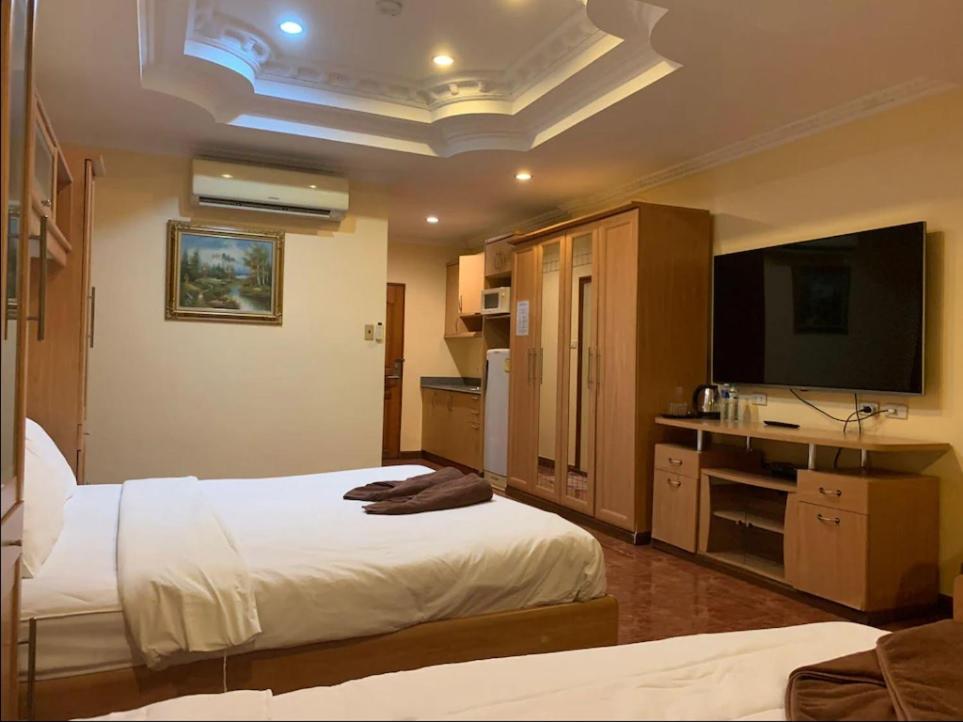 a hotel room with two beds and a flat screen tv at Pauna Inn Pattaya in Pattaya South