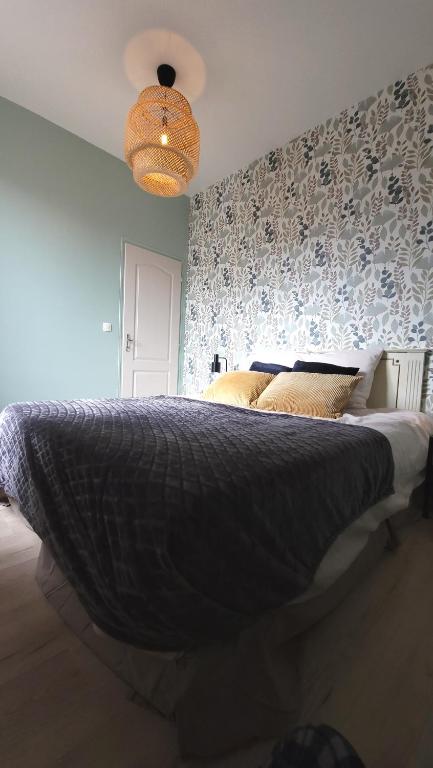 a bedroom with a large bed with a patterned wall at Gite Urbain - La Capsule - Parking in Épernay