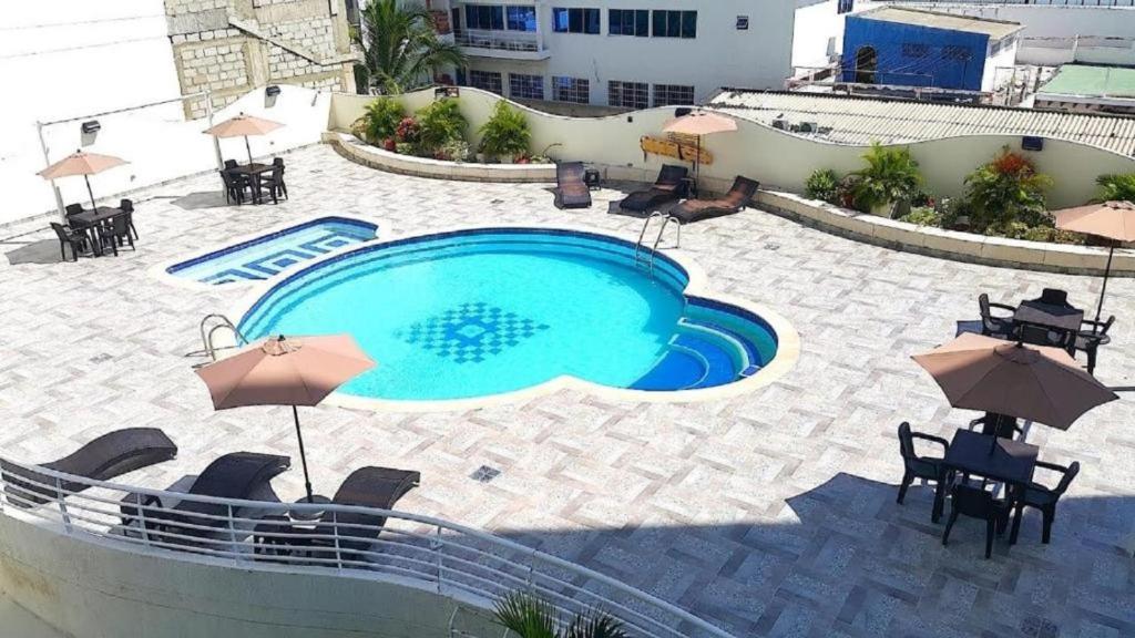 聖瑪爾塔的住宿－Santa Marta Apartamentos - Brisas Marina，一个带桌椅和遮阳伞的游泳池