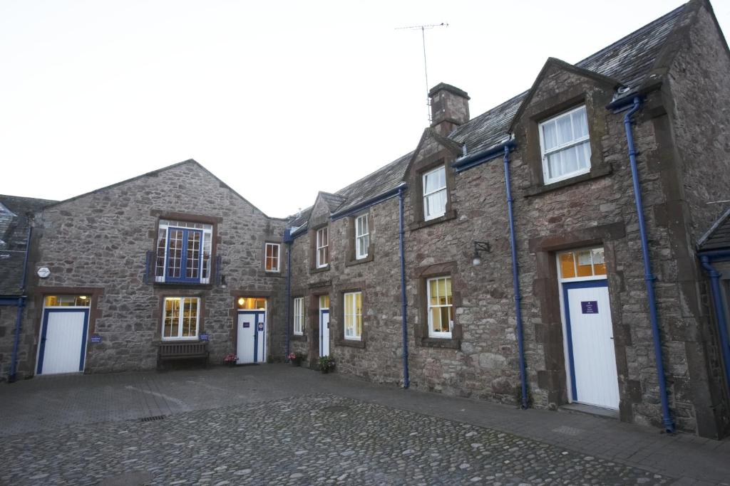 a row of stone buildings with white doors at Muncaster Castle Coachman's Quarters in Ravenglass