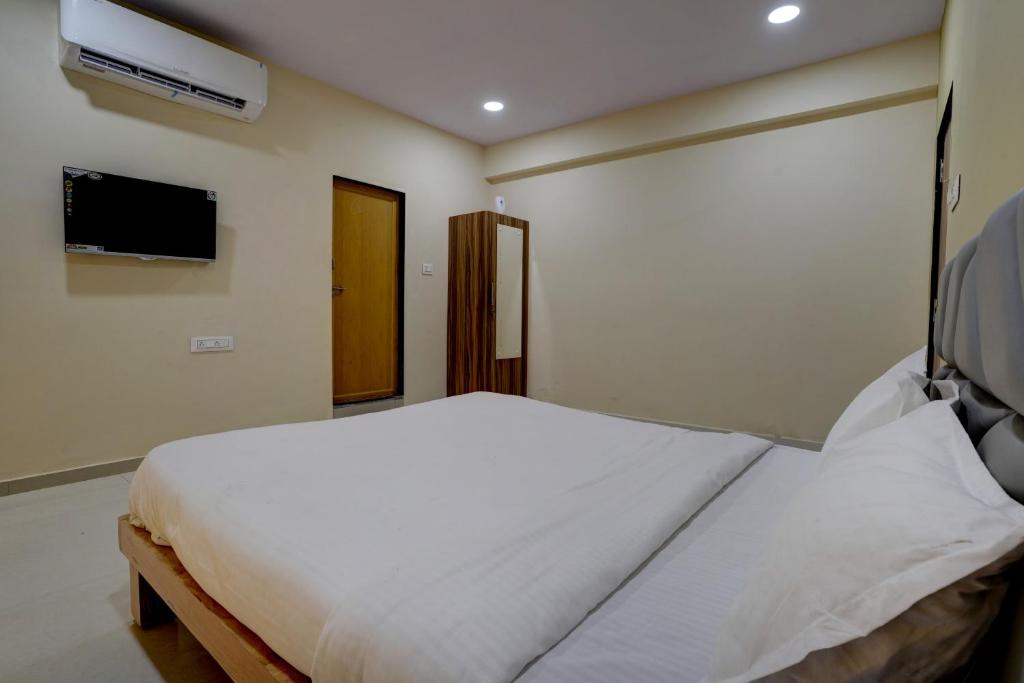 a bedroom with a white bed and a tv at OYO Hotel 7 Star in Surat