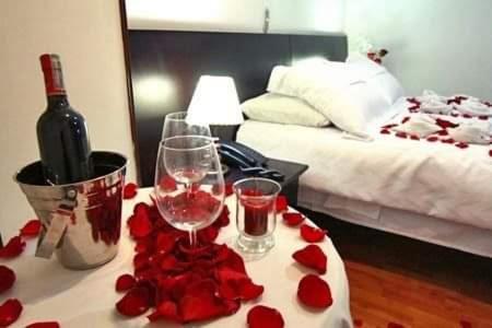 HOTEL MIRADOR LOS ANDES في Mojón de Lima: طاولة مع كأسين من النبيذ والورود الحمراء