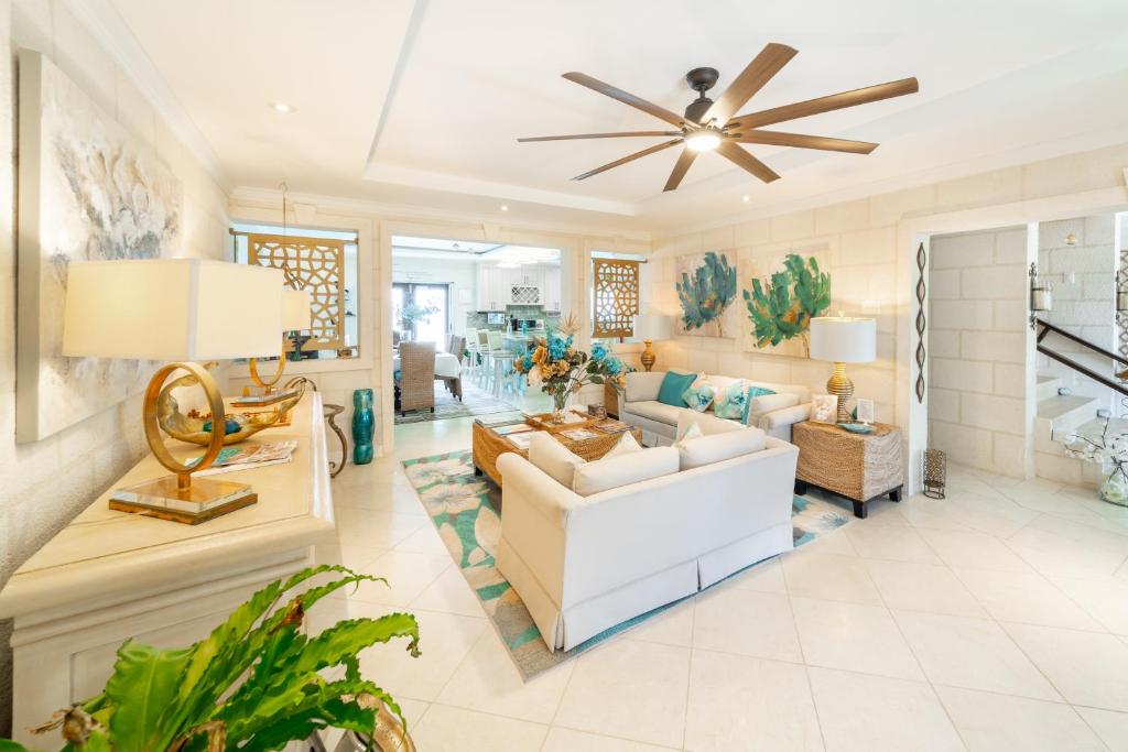 a living room with a white couch and a ceiling fan at Hidden Gem Barbados in Christ Church