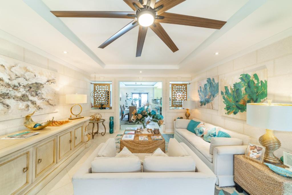 a living room with a white couch and a ceiling fan at Hidden Gem Barbados in Christ Church