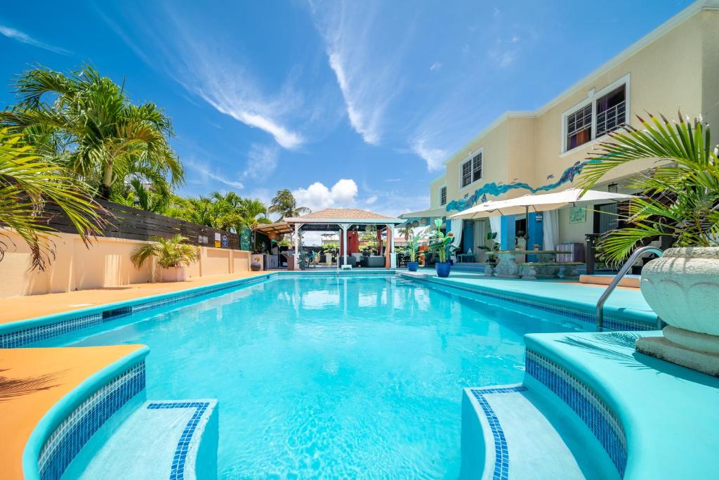 a swimming pool with palm trees and a building at Hidden Gem Barbados in Christ Church