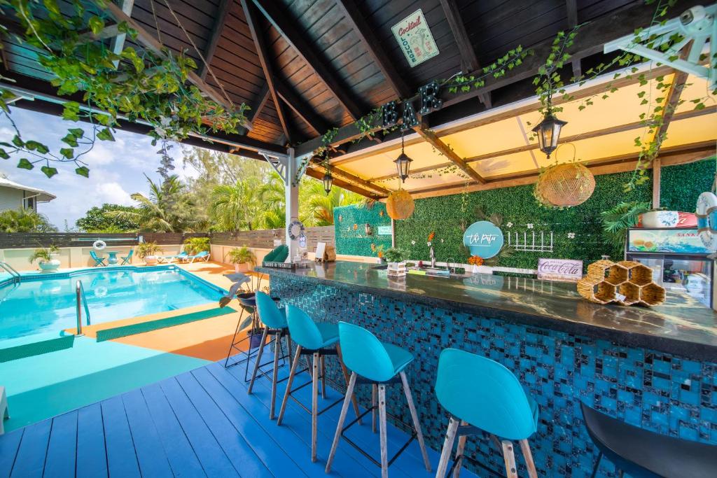 a poolside bar with blue chairs and a swimming pool at Hidden Gem Barbados in Christ Church