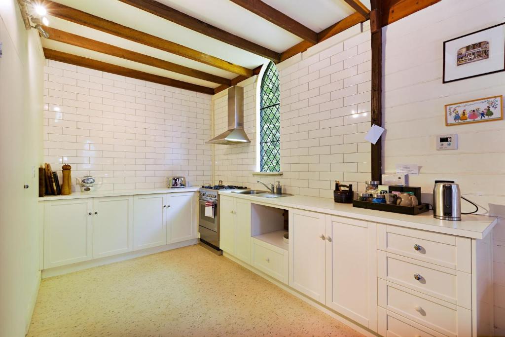 a large kitchen with white cabinets and a window at Blue Gum Church in Beechworth
