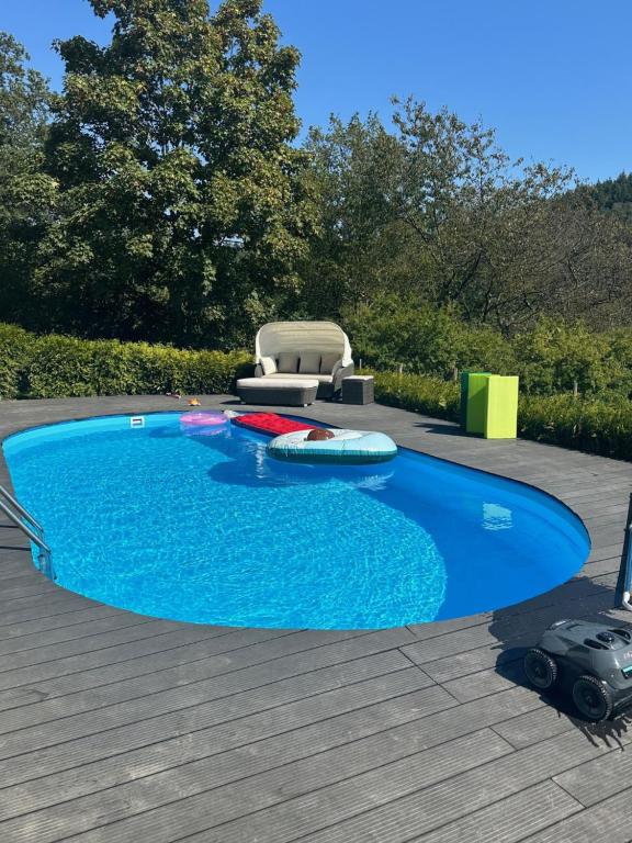 una piscina azul con una silla y una mesa en Ferienwohnung Panorama Oberkirn, en Oberkirn