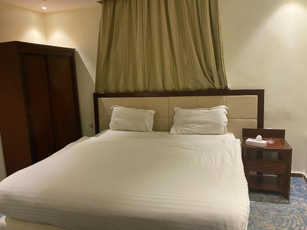 a bedroom with a large white bed and a table at شقق الرياده الفاخره in Jeddah
