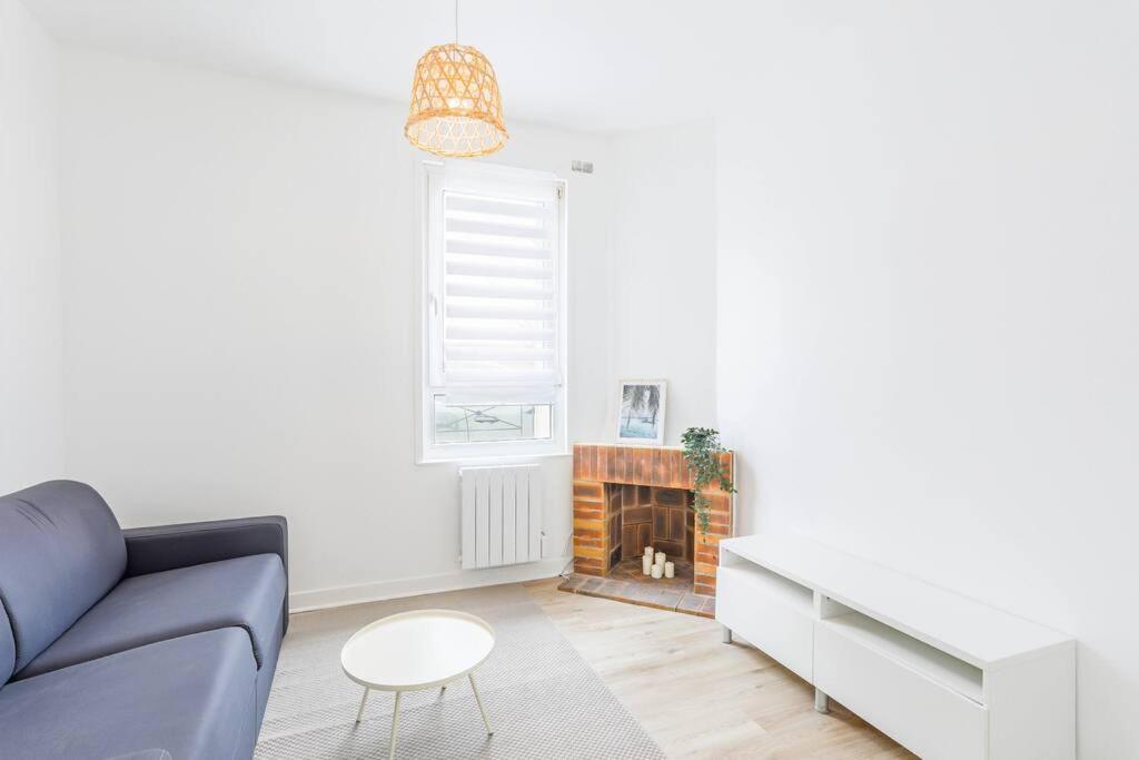 un salon avec un canapé et une cheminée dans l'établissement Logement avec jardin 19min Paris, à Eaubonne